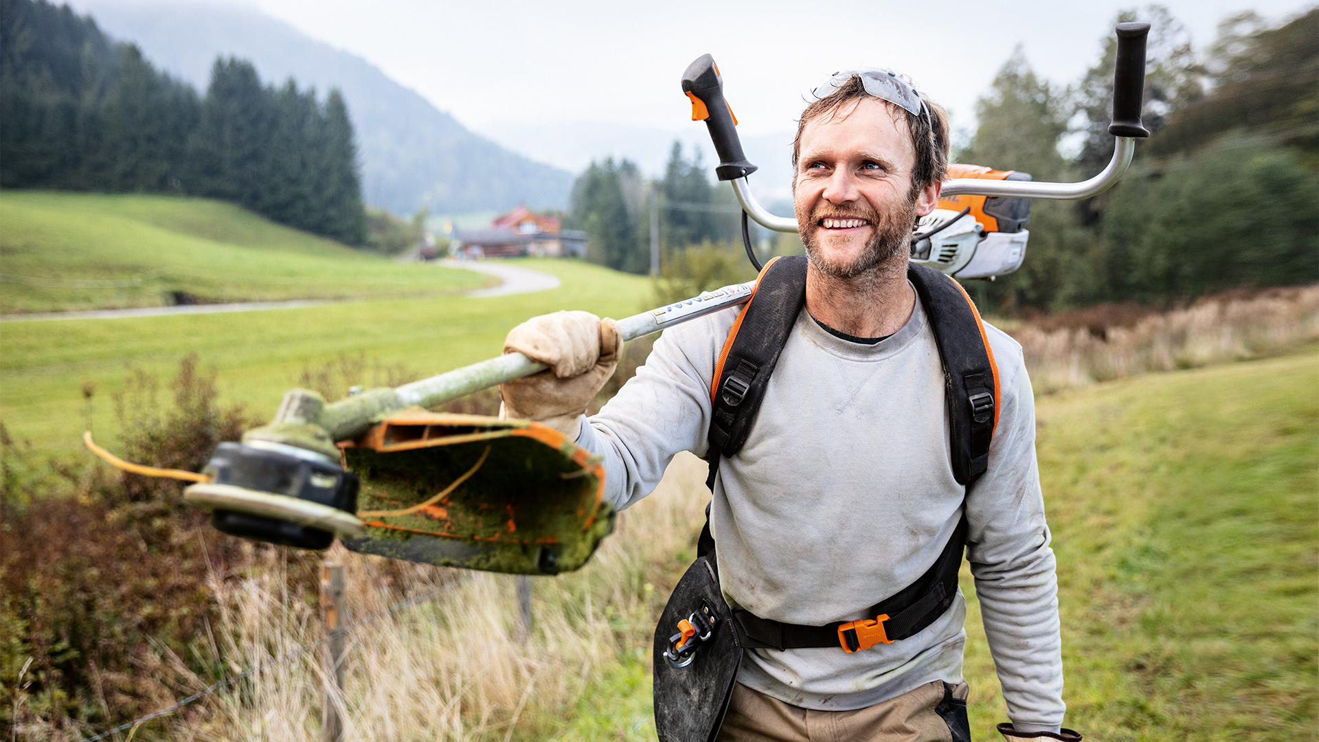 Mand med STIHL buskrydder og Advance PLUS universal bælte på en eng
