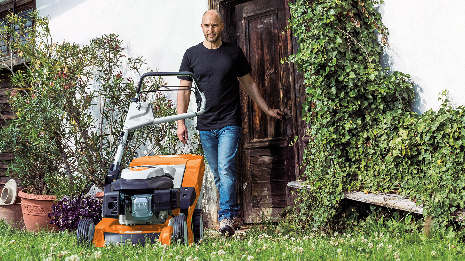 Manden går fra døren ind i haven til en STIHL RM 650 benzinplæneklipper