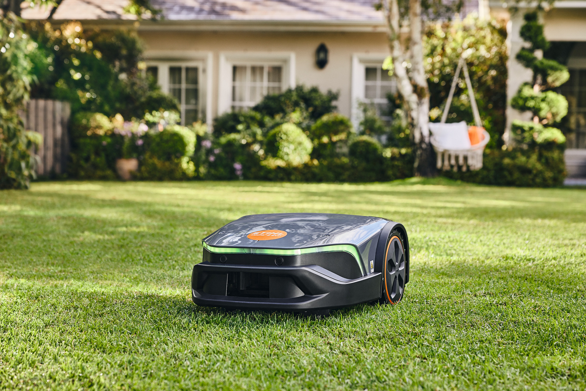 En STIHL iMOW® robotplæneklipper på en grøn plæne i haven