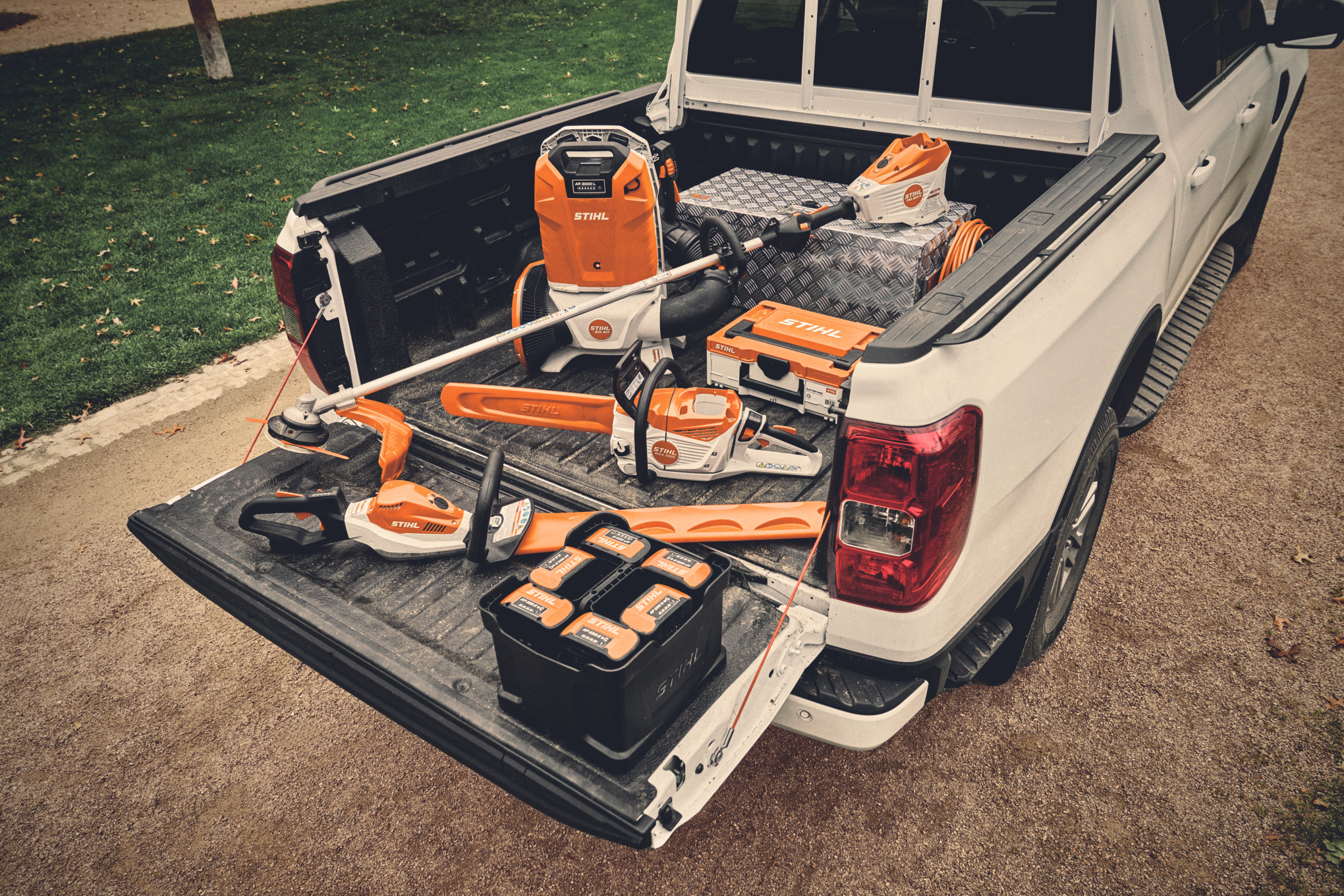 Forskellige batteridrevne maskiner og passende batterier fra STIHL AP-systemet på ladet af en bil  
