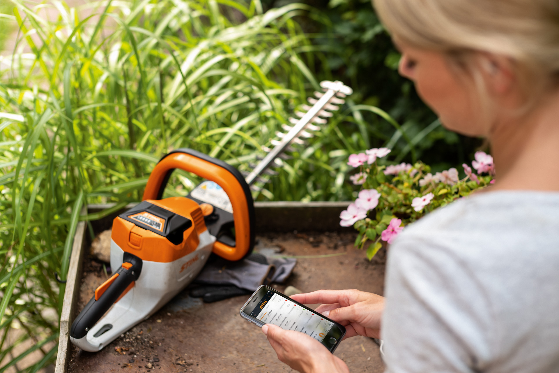 En kvinde registrerer sin STIHL-hækkeklipper via STIHL-appen på sin smartphone.