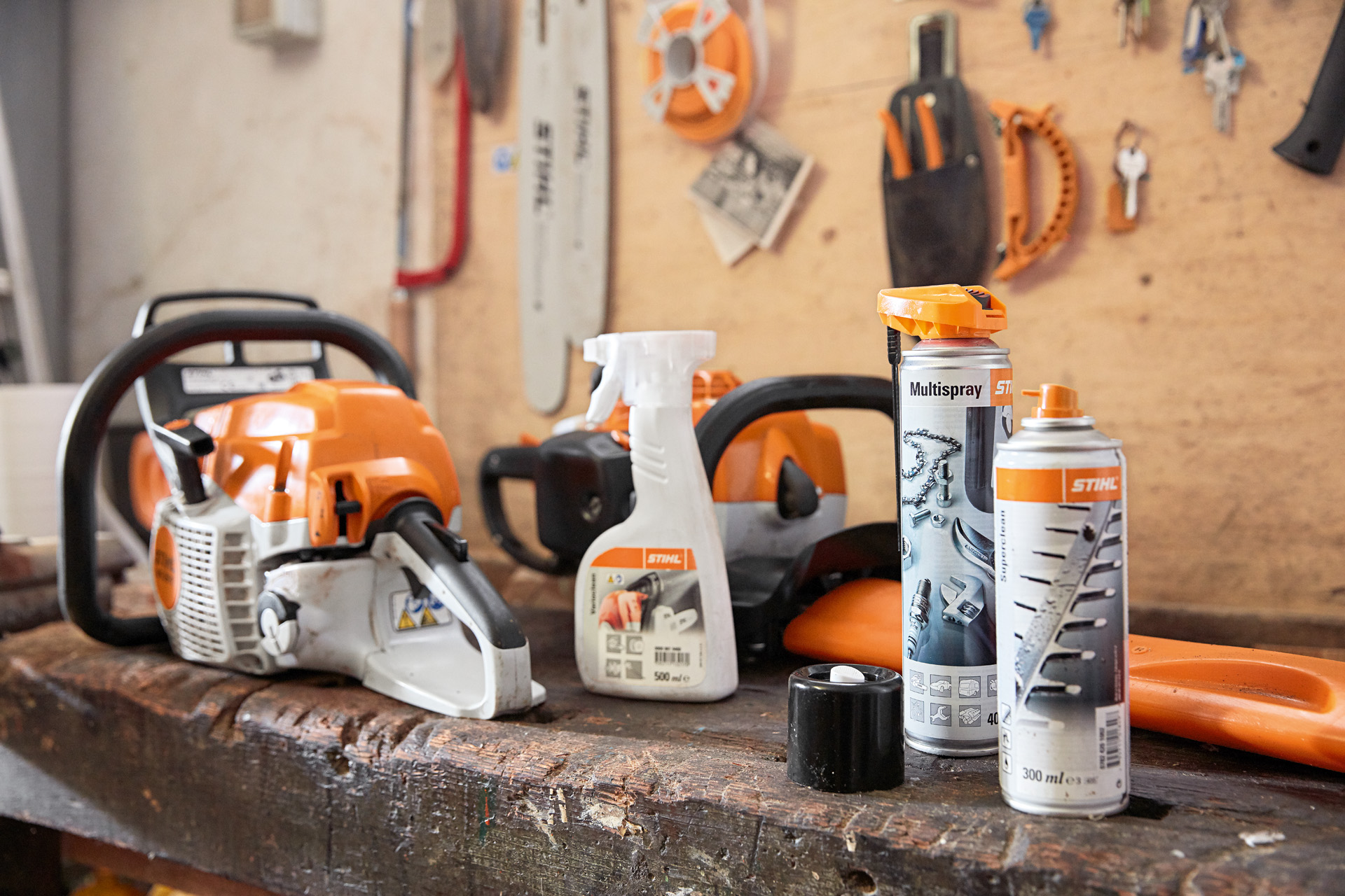 En arbejdsbænk med flere STIHL produkter på: en motorsav, Varioclean, Multispray og Superclean harpiksopløsningsmiddel