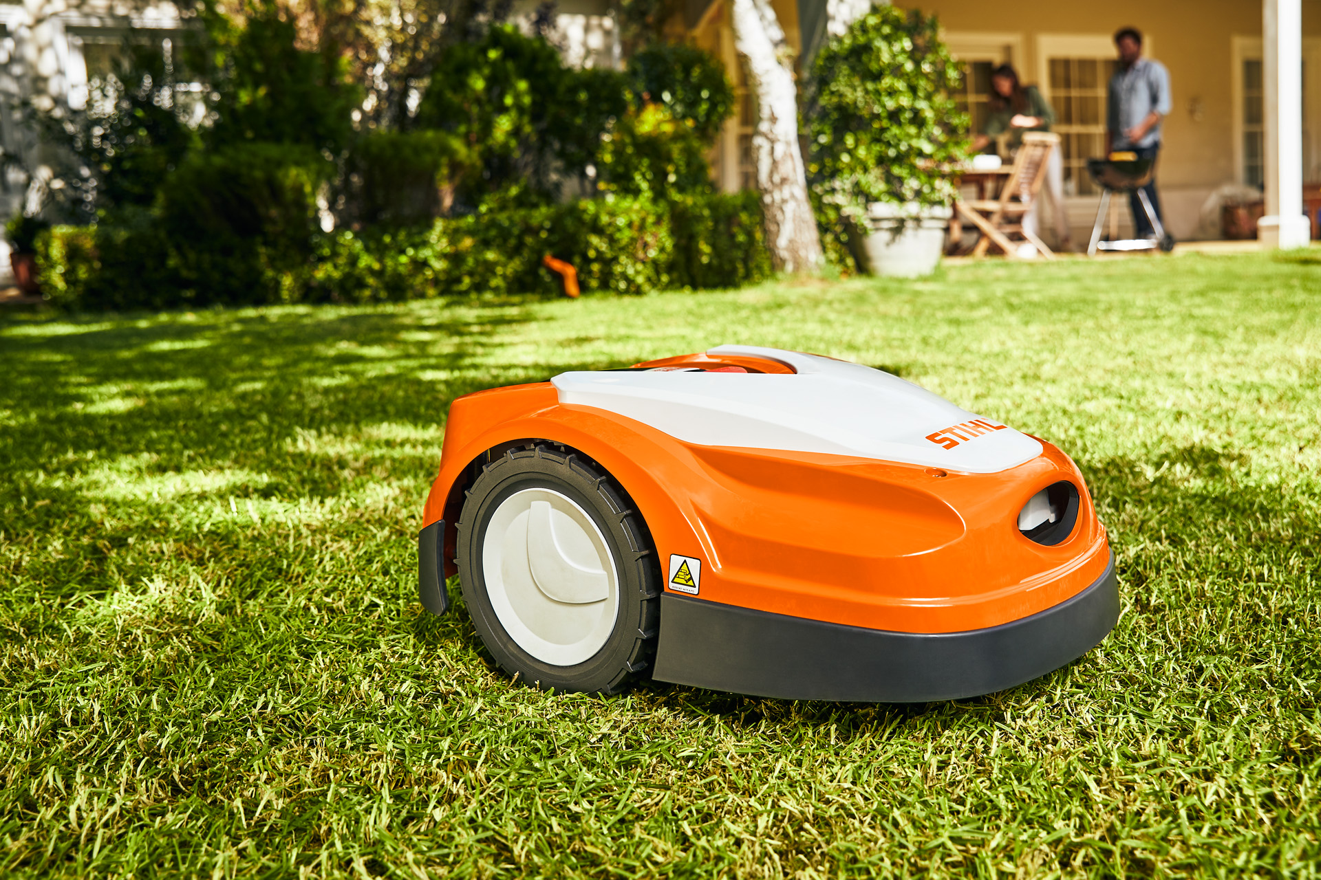 STIHL iMOW® RI 422 robotplæneklipper på en grøn græsplæne foran et hus