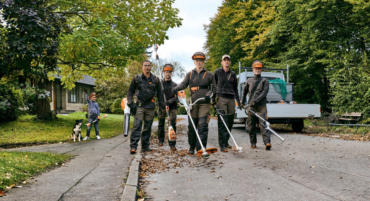 Et have- og landskabsarkitekturteam med professionelle STIHL-batteriværktøjer går langs en gade.