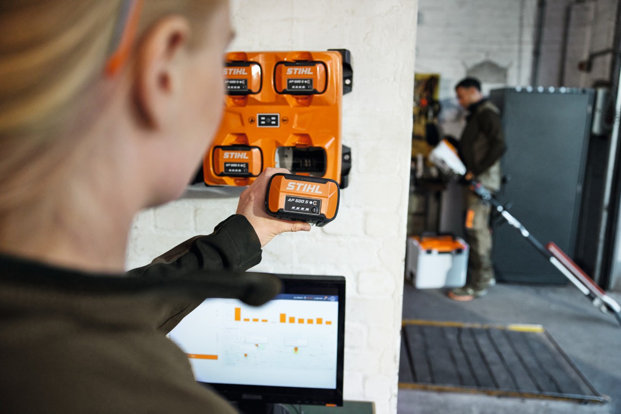 En kvinde foran en bærbar computer fjerner en AP 300 S fra en STIHL AL 301-4 multioplader