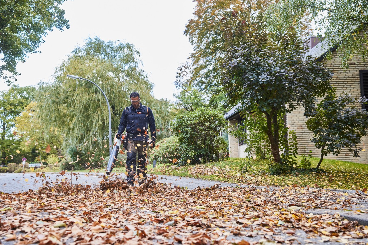 En have- og landskabsarkitekt fjerner blade fra en vej med en STIHL BGA 200 batteridrevet løvblæser.