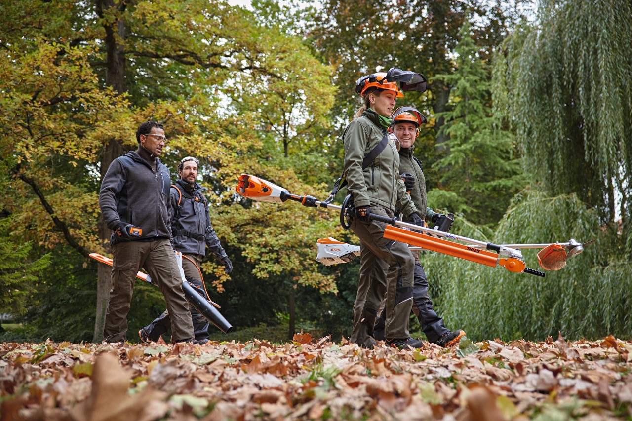 Fire STIHL-professionelle med batteridrevne værktøjer, der går langs en sti