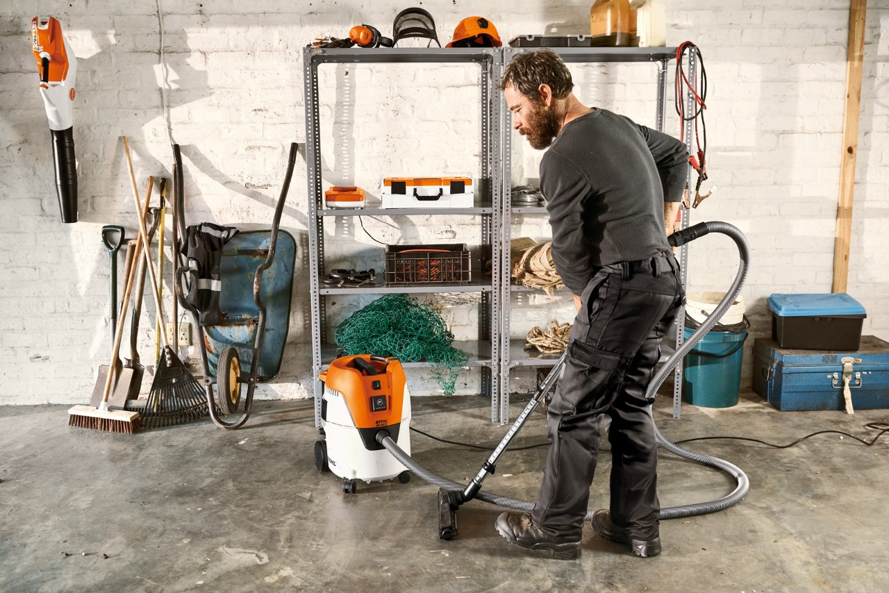Mand, der støvsuger gulvet i en garage med en STIHL SE 62 E våd-/tørstøvsuger