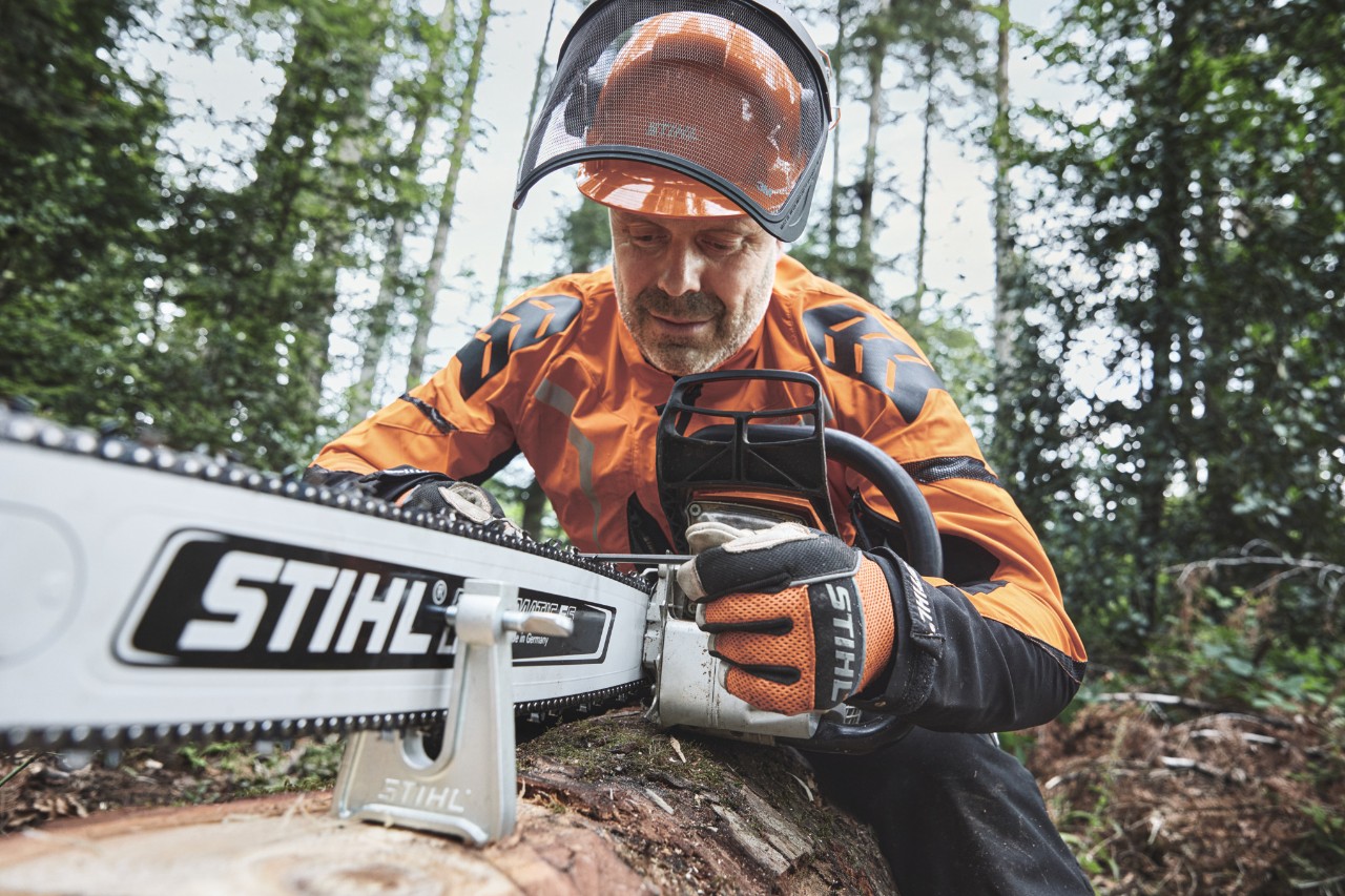 En mand iført beskyttelsesudstyr arbejder med en STIHL-motorsav i en skov