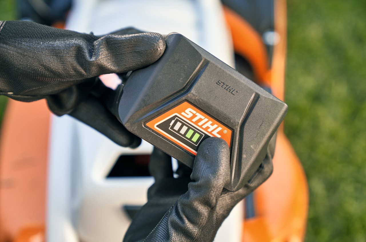 STIHL lithium-ion-batteri med en STIHL RMA 339 C batteriplæneklipper i baggrunden