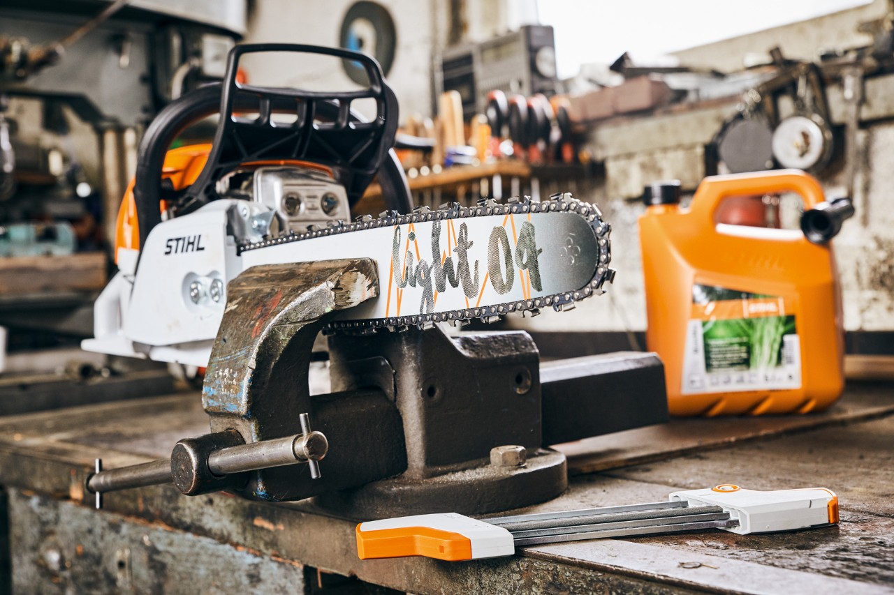 STIHL MS 261 C-M benzinmotorsav med Light 04-sværd ved siden af STIHL MotoMix-brændstofblanding før slibning