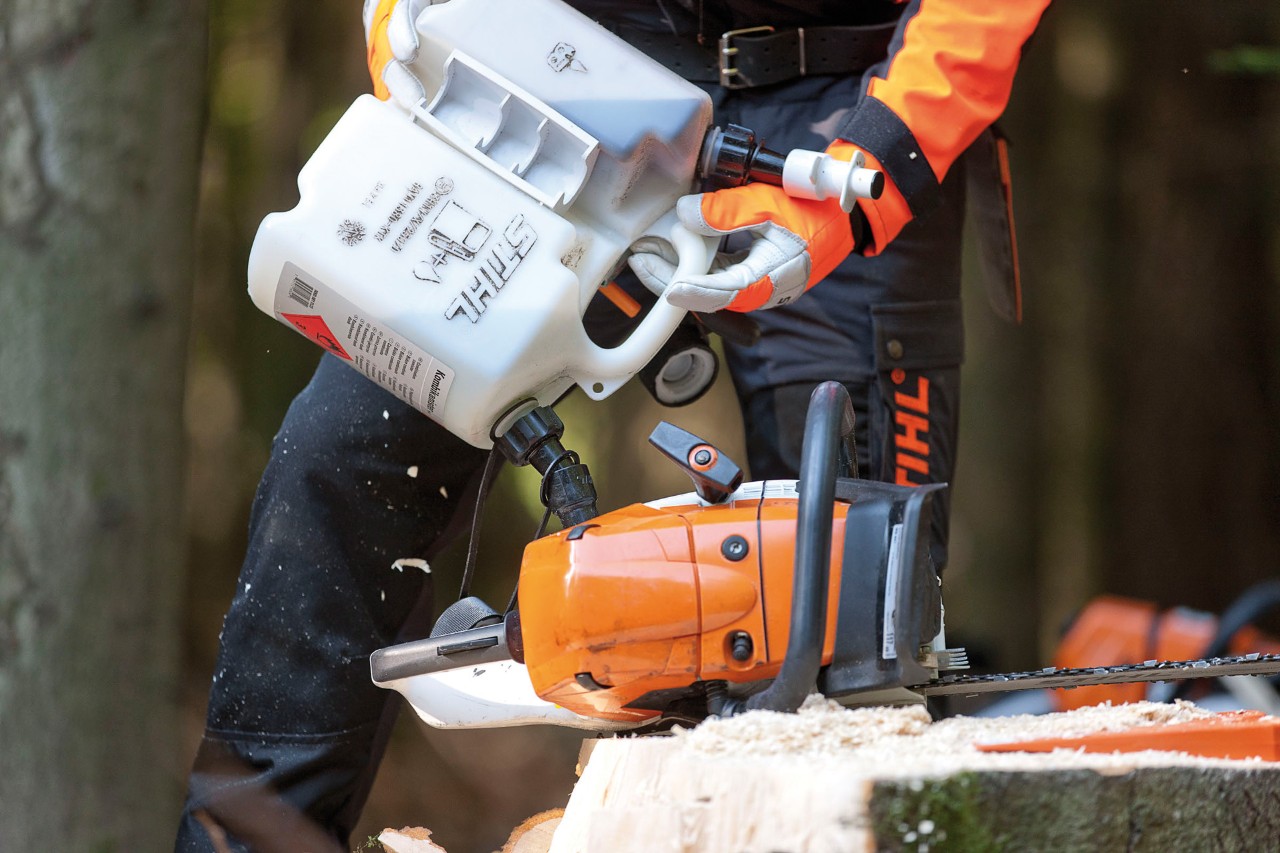 Selvblandet motorsavbenzin hældes fra en brændstofdunk i en motorsav STIHL MS 441