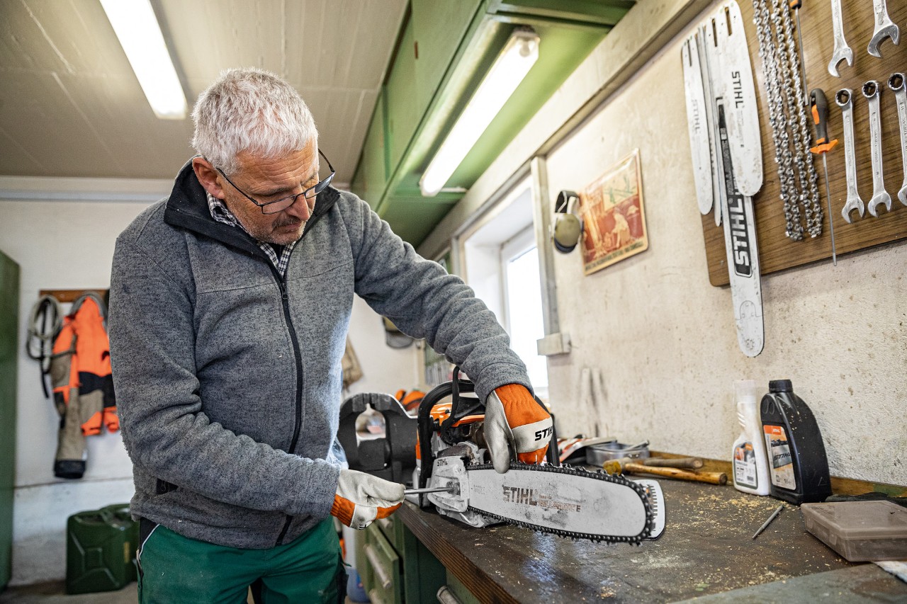 En mand spænder en STIHL-motorsavskæde på et værksted