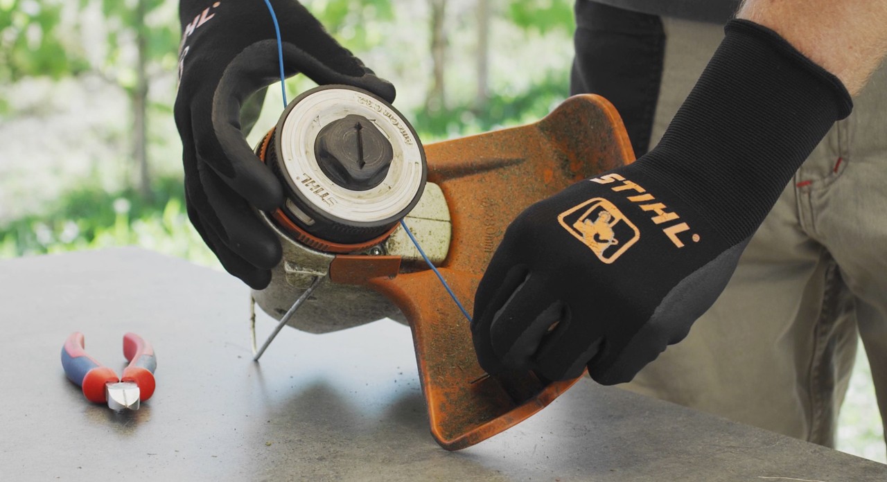 Person, der vikler trimmertråden op på en STIHL FSA 57 batteridrevet buskrydder
