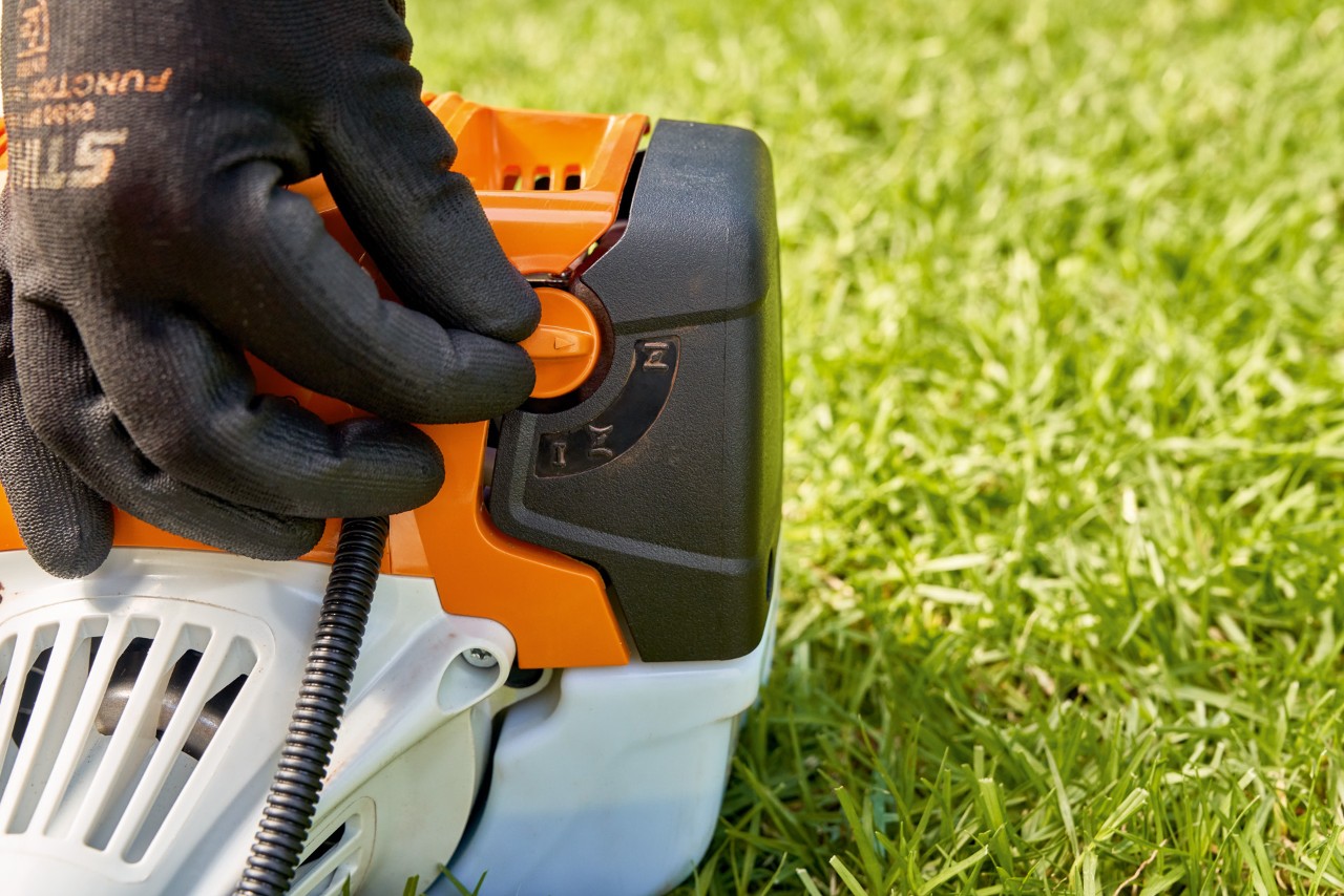 En mand justerer brændstofpumpen på en STIHL FS 91 benzindrevet buskrydder for at starte den