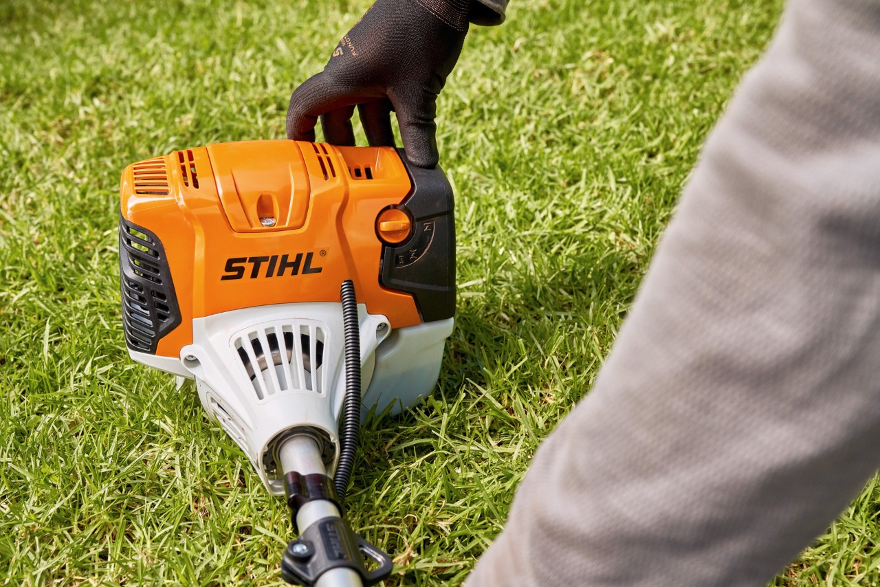 Mand, der trykker en STIHL FS 91 benzindrevet buskrydder fast på jorden