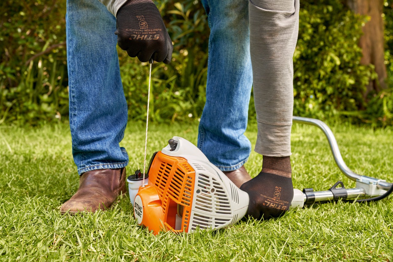 Mand trækker i startsnoren på en STIHL FS 56 benzindrevet buskrydder 