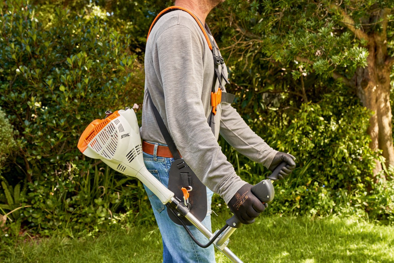 En mand løfter en STIHL FS 56 benzindrevet buskrydder fra jorden