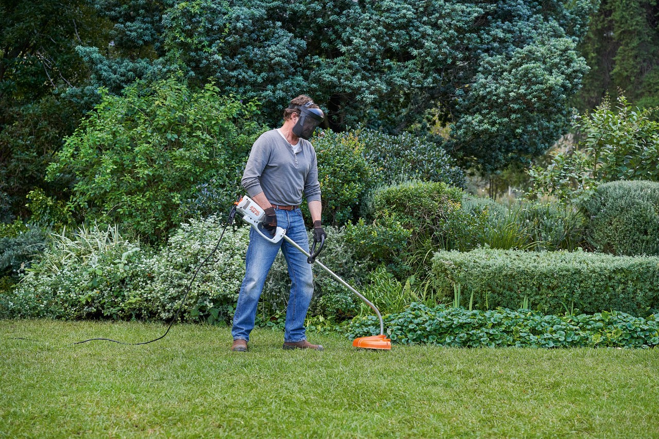 En mand står sikkert på fødderne med en elektrisk buskrydder STIHL FSE 60
