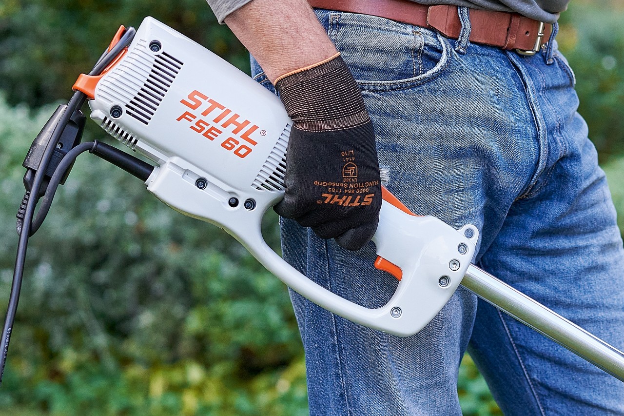 Mand trykker på kontakten for at slukke for den elektriske buskrydder STIHL FSE 60.