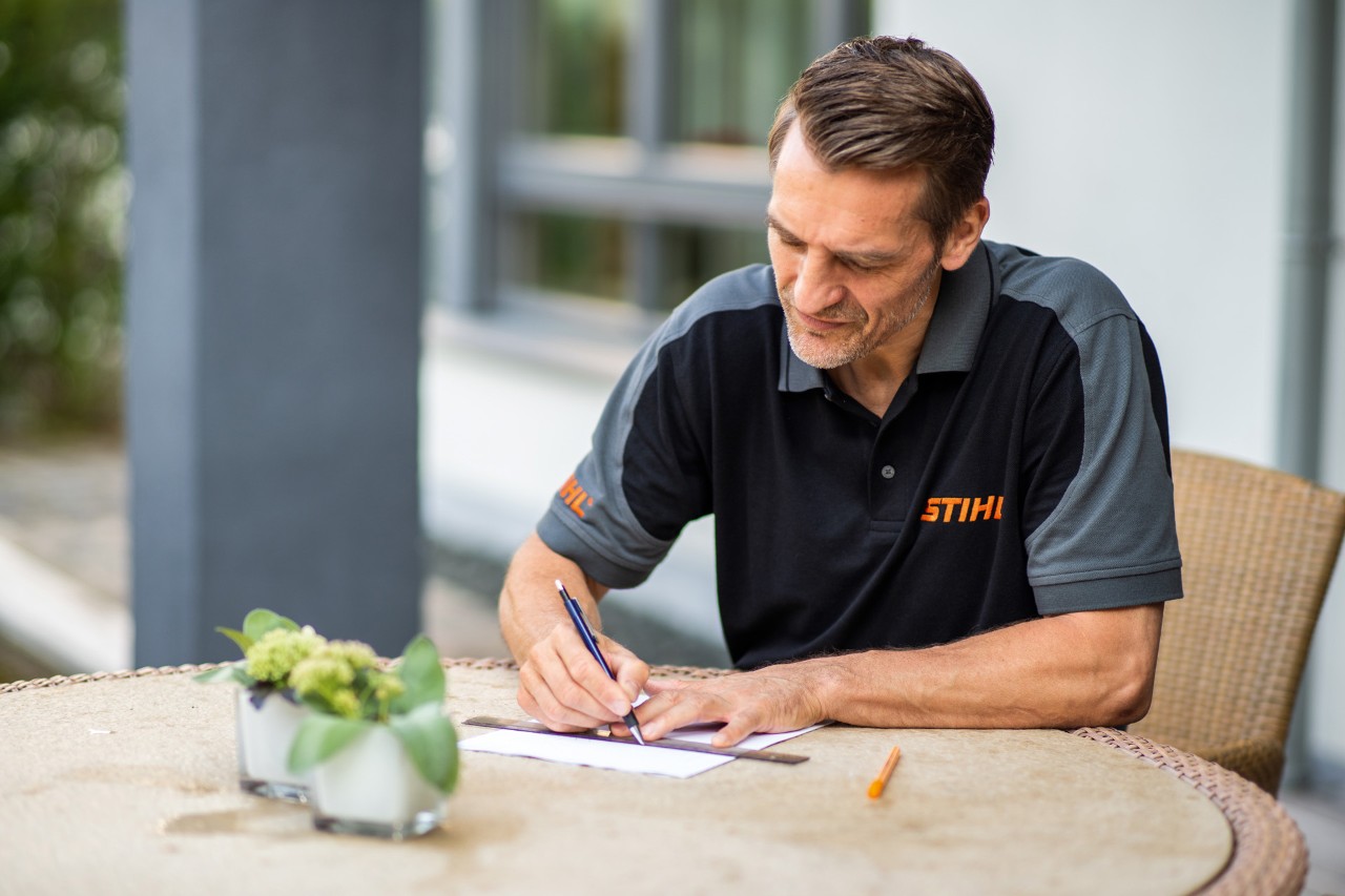 En STIHL-forhandler optegner et plæneareal til en STIHL iMOW® 422 robotplæneklipper