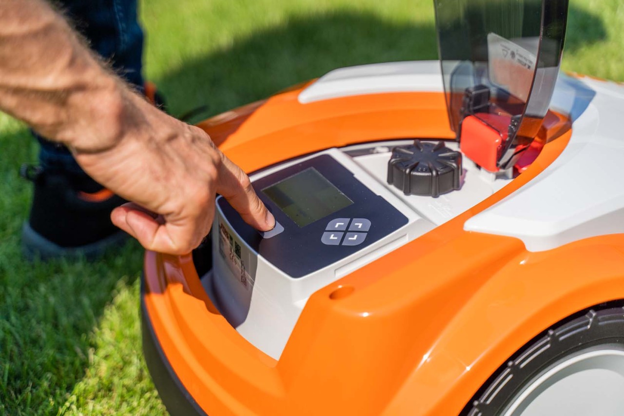 Betjeningspanelet på en STIHL iMOW® 422 robotplæneklipper, mens nogen trykker på en af knapperne