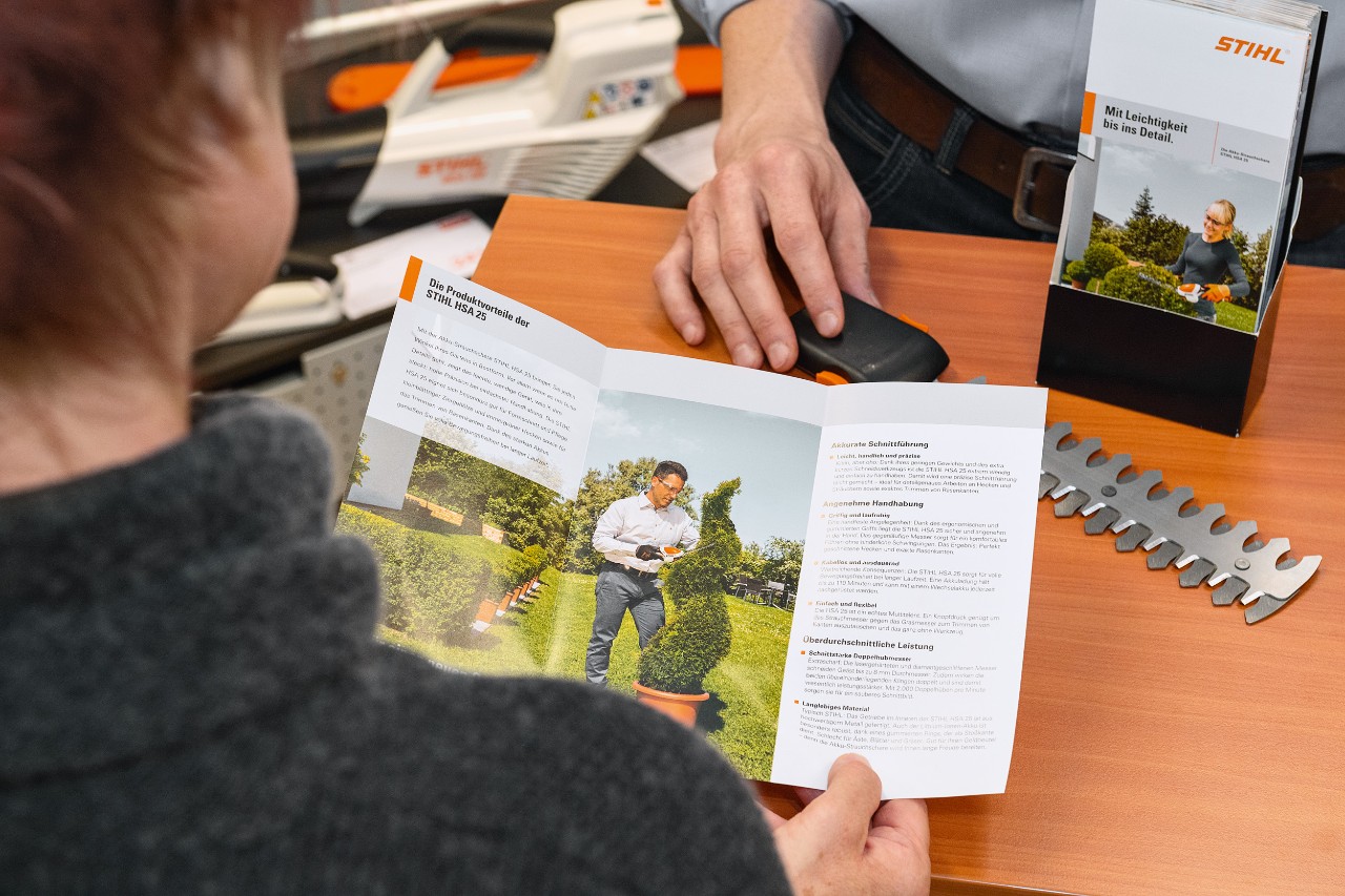 En person, der læser om produktfordelene ved STIHL HSA 25 i en brochure