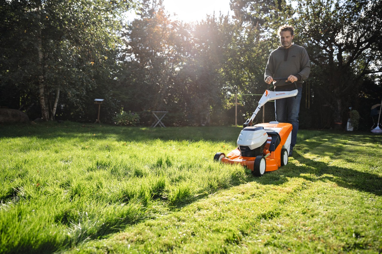 En mand klipper en græsplæne med en STIHL RMA 448 VC batteriplæneklipper