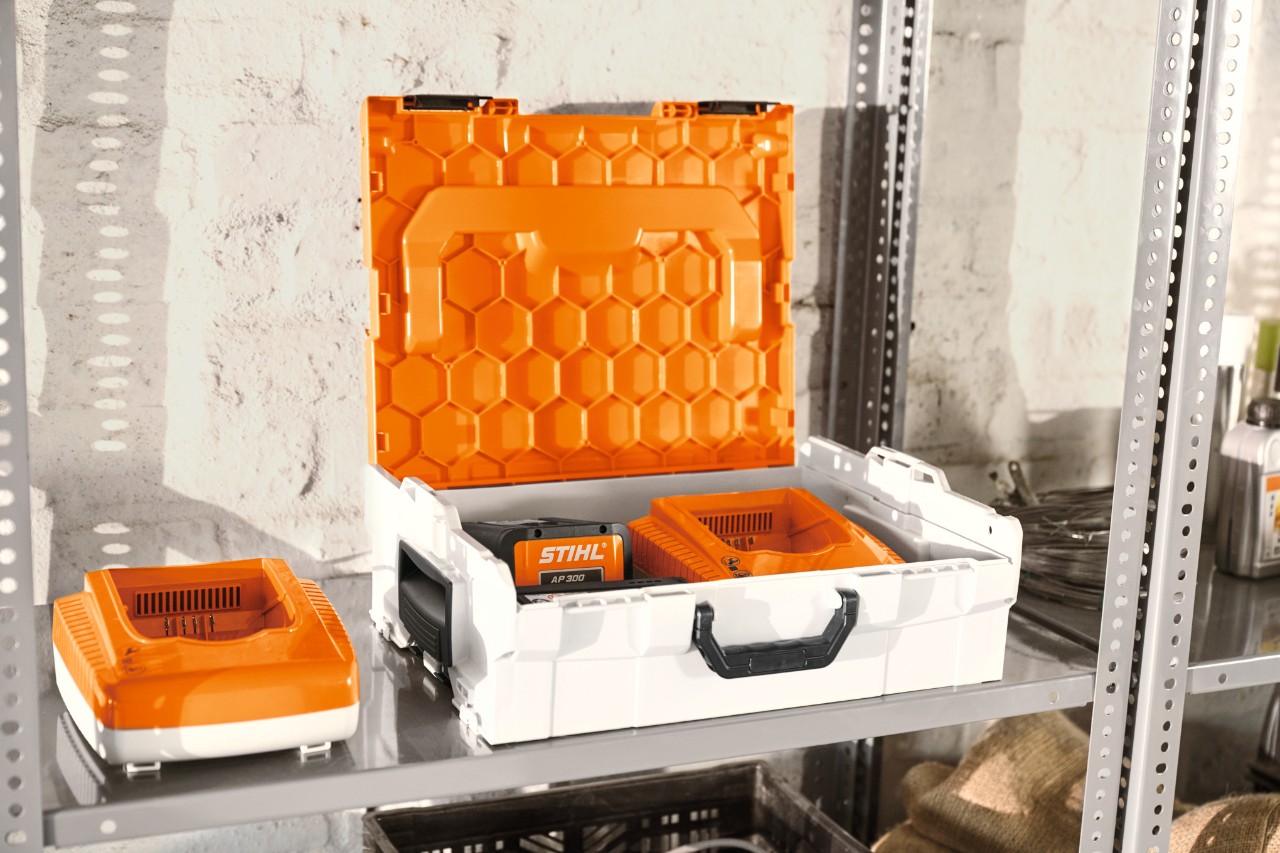 STIHL-batteriboks med STIHL-batterier på en værkstedsreol  