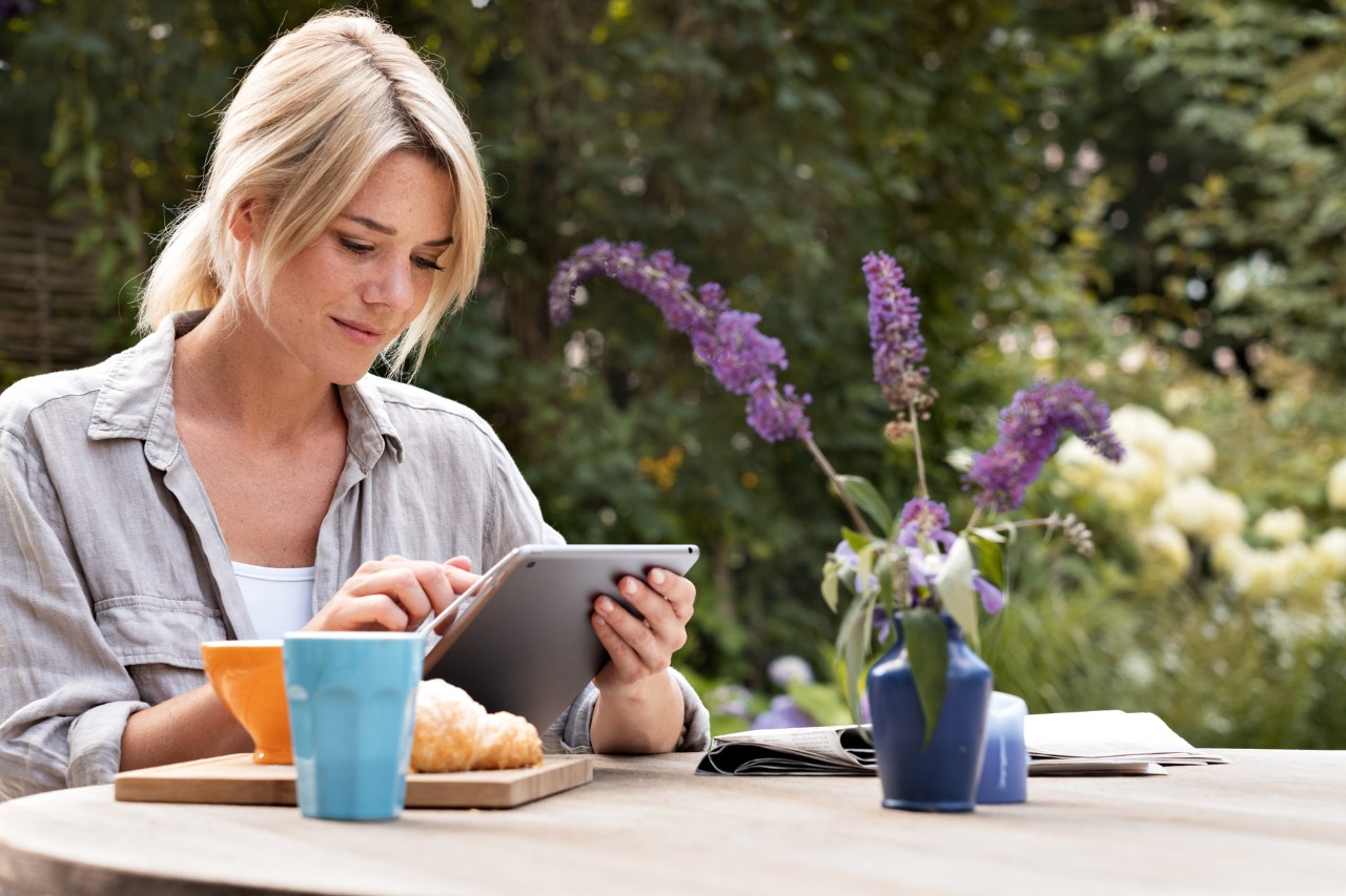 En kvinde, der bruger en tablet, mens hun sidder ved et bord udenfor