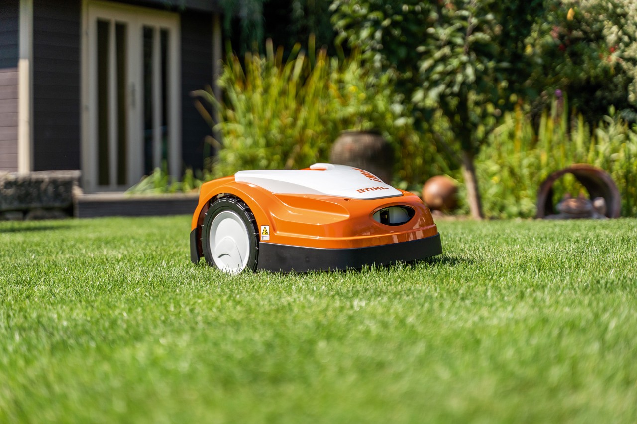 En STIHL iMOW® RMI 422 robotplæneklipper på en grøn græsplæne foran et hus